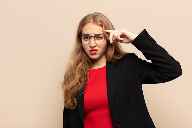 Blonde woman feeling confused and puzzled, showing you are insane, crazy or out of your mind