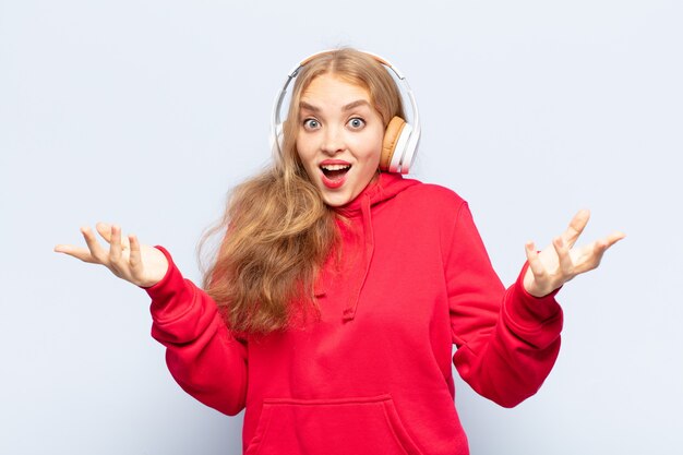 Blonde woman feeling extremely shocked and surprised, anxious and panicking, with a stressed and horrified look