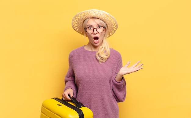 Blonde woman feeling extremely shocked and surprised, anxious and panicking, with a stressed and horrified look