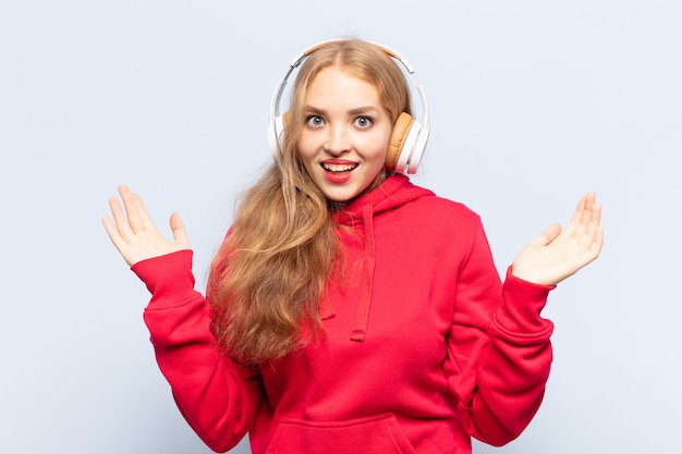 Blonde woman feeling happy, excited, surprised or shocked, smiling and astonished at something unbelievable