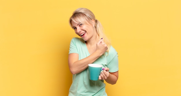 Blonde woman feeling happy, positive and successful, motivated when facing a challenge or celebrating good results