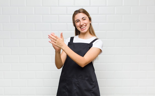 Donna bionda che si sente felice e di successo, sorridente e battendo le mani, dicendo congratulazioni con un applauso