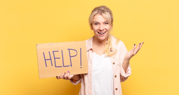 Foto donna bionda che si sente felice, sorpresa e allegra, sorridente con atteggiamento positivo, realizzando una soluzione o un'idea