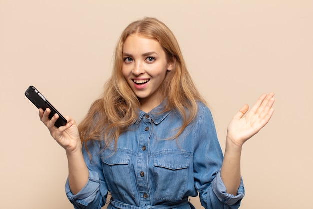 Donna bionda che si sente felice, sorpresa e allegra, sorridente con atteggiamento positivo, realizzando una soluzione o un'idea