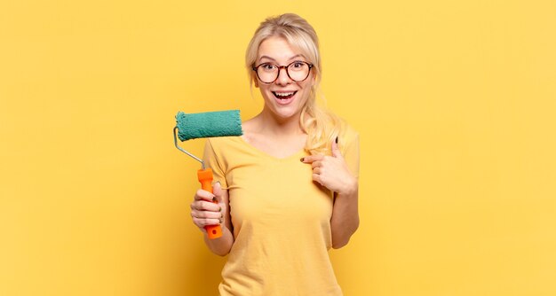 Blonde woman feeling happy, surprised and proud, pointing to self with an excited, amazed look