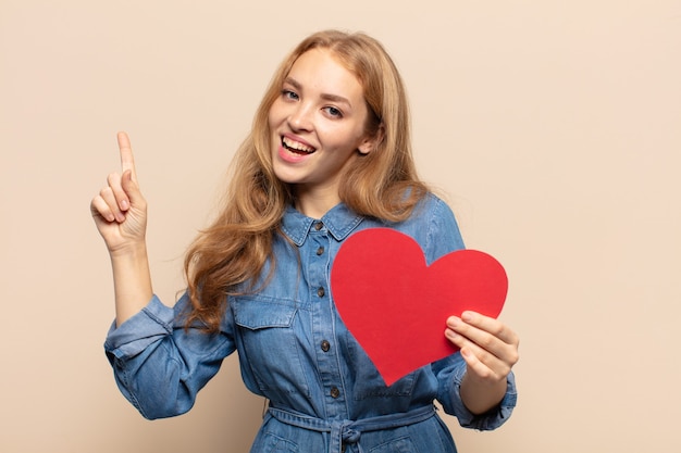 Blonde woman feeling like a happy and excited genius after realizing an idea, cheerfully raising finger, eureka!