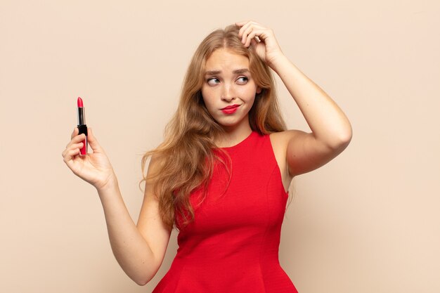 Blonde woman feeling puzzled and confused, scratching head and looking to the side