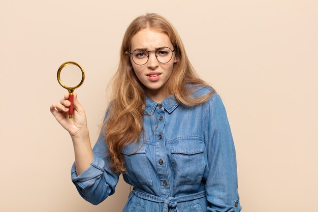 Blonde woman feeling puzzled and confused, with a dumb, stunned expression looking at something unexpected