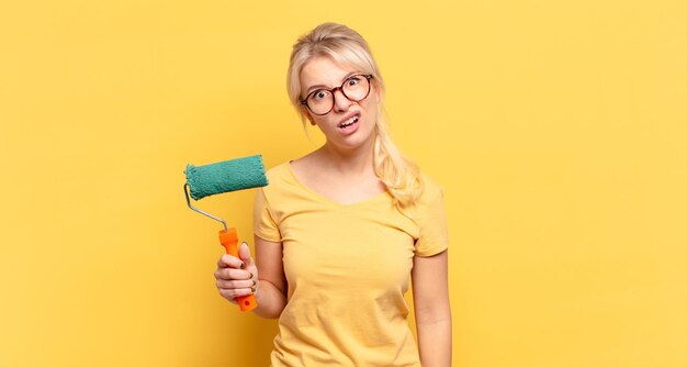 Blonde woman feeling puzzled and confused, with a dumb, stunned expression looking at something unexpected