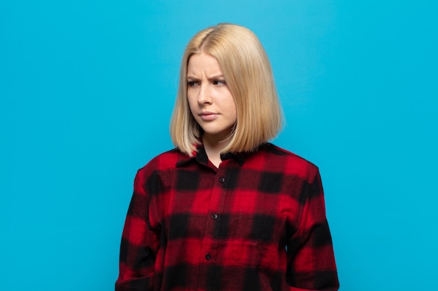 Blonde woman feeling sad, upset or angry and looking to the side with a negative attitude, frowning in disagreement