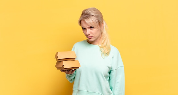 Blonde woman feeling sad, upset or angry and looking to the side with a negative attitude, frowning in disagreement