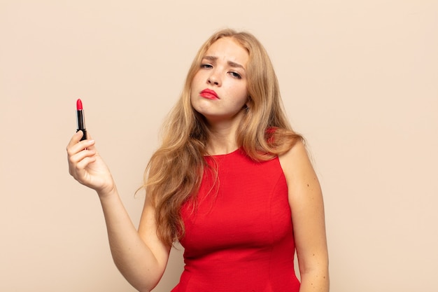 Blonde woman feeling sad and whiney with an unhappy look, crying with a negative and frustrated attitude