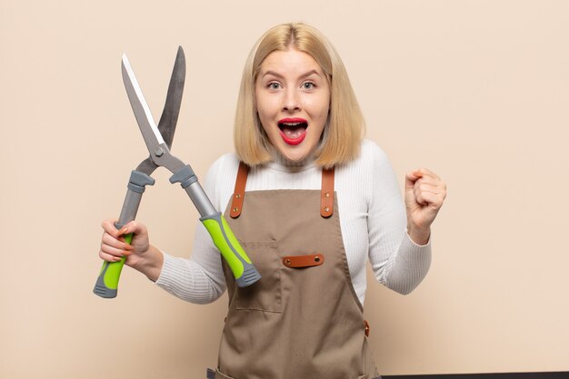 Blonde woman feeling shocked, excited and happy, laughing and celebrating success, saying wow!