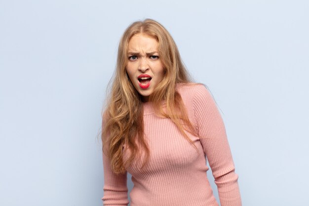 Blonde woman feeling terrified and shocked, with mouth wide open in surprise