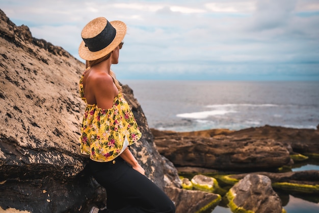 Blonde woman in a floral shirt at the rocky beach