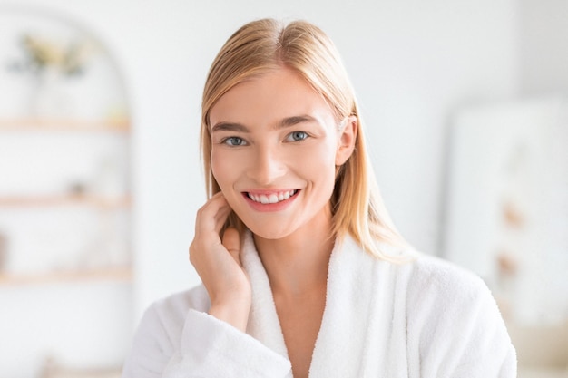 blonde woman gently touches her face in bathroom