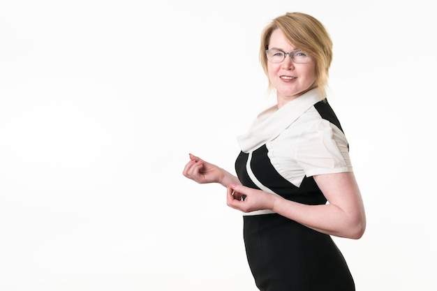 Blonde woman in glasses dressed in blackwhite dress looking at camera Mature adult businesswoman