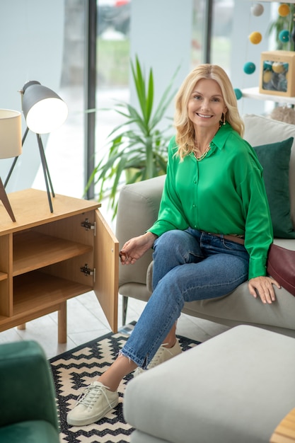 Blonde woman in a green blouse looking contented