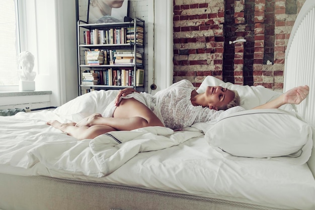 Photo a blonde woman has just woken up in the morning and is lying in bed dreaming