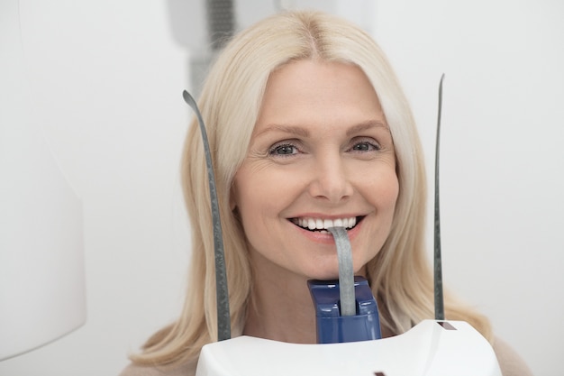 Foto una donna bionda che si sottopone a cure dentistiche e si sente positiva