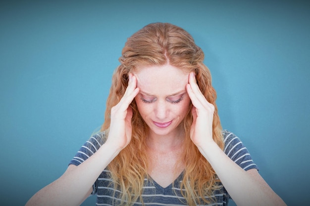 Foto una donna bionda che ha mal di testa su sfondo blu