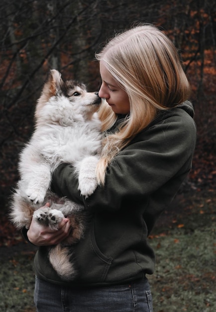 blonde woman holding a puppy dog kissing