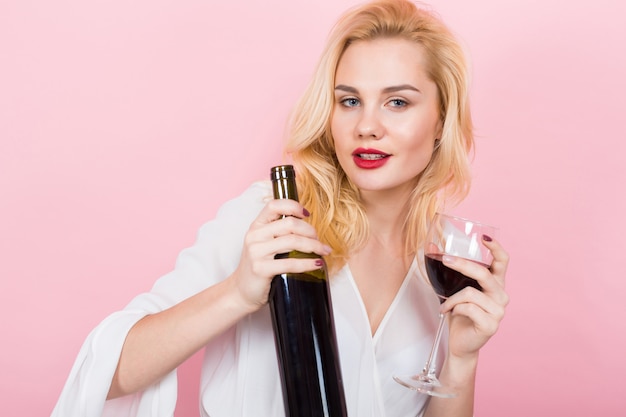 Blonde woman holding wine bottle and glass