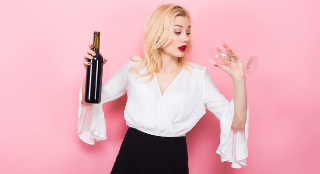 Blonde woman holding wine bottle and glass