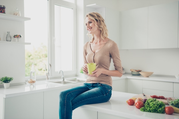 Blonde woman at home in the kitchen with vegetables