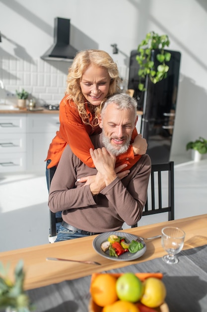 Blonde woman hugging her husband and both looking happy