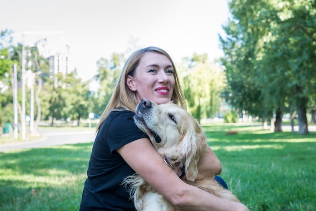 Blonde woman hugs retriever dog outdoors