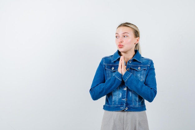 The blonde woman is asking by holding hands together on chest  on white background