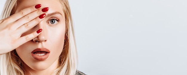 The blonde woman is surprised badly covers half of her on a white isolated background