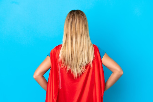 Photo blonde woman over isolated background in superhero costume in back position