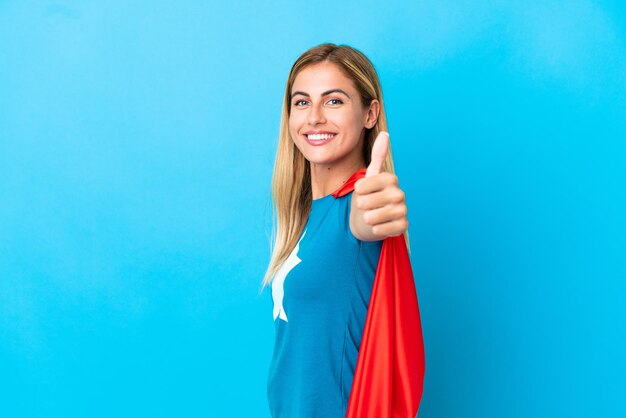 Blonde woman over isolated background in superhero costume with thumb up