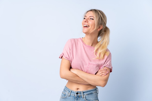 Blonde woman over isolated blue background happy and smiling