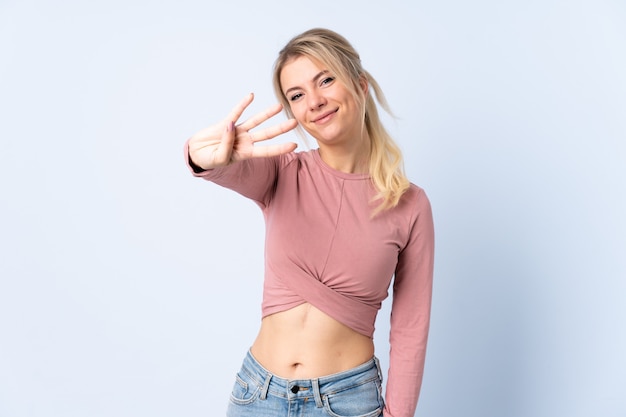 Blonde woman over isolated blue happy and counting four with fingers