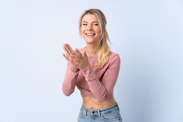 Blonde woman over isolated blue wall applauding after presentation in a conference