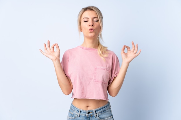 Blonde woman over isolated blue in zen pose