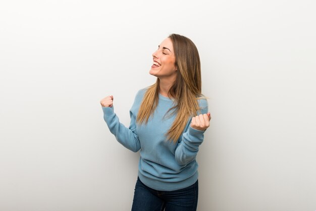 Blonde woman on isolated white background celebrating a victory