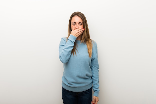 Blonde woman on isolated white background covering mouth with hands for saying something inappropriate