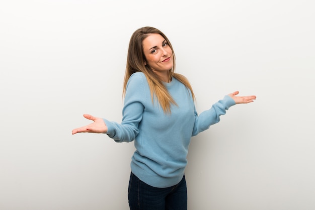 Blonde woman on isolated white background making unimportant gesture while lifting the shoulders