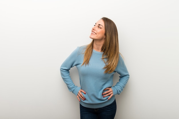 Blonde woman on isolated white background posing with arms at hip and laughing