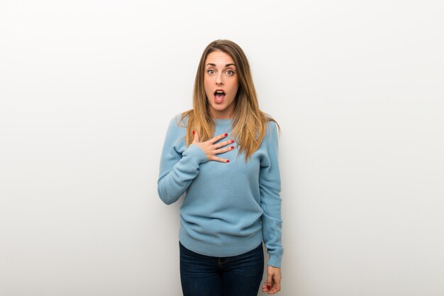 Blonde woman on isolated white wall surprised and shocked while looking right