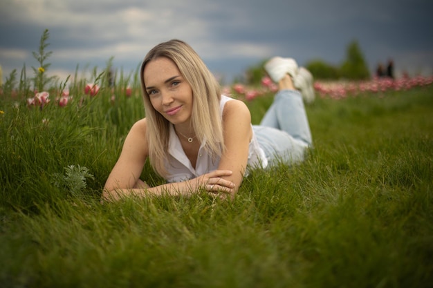 Blonde woman lies on the grass with tulips