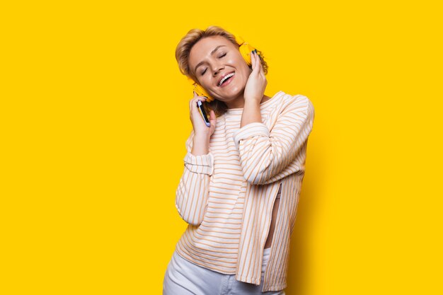 Blonde woman listen music on colorful background pretty young woman dancing on studio wall with head...