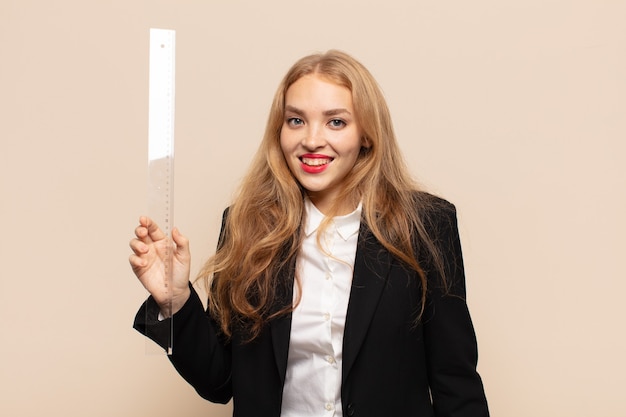 Blonde woman looking happy and pleasantly surprised, excited with a fascinated and shocked expression