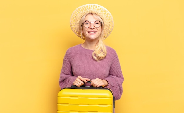 Blonde woman looking happy and pleasantly surprised, excited with a fascinated and shocked expression