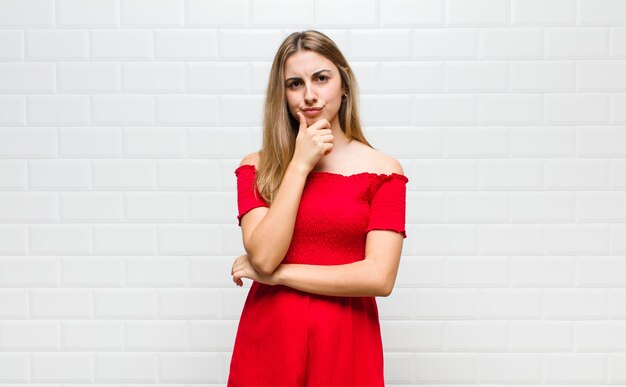 Blonde woman looking serious, confused, uncertain and thoughtful, doubting among options or choices