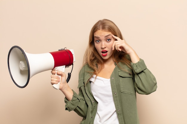 Blonde woman looking surprised, open-mouthed, shocked, realizing a new thought, idea or concept